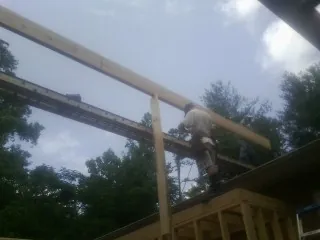 Carpenter setting a ridge beam over a new addition frame — Ice Dam Removal by Roofing Brothers in Counce