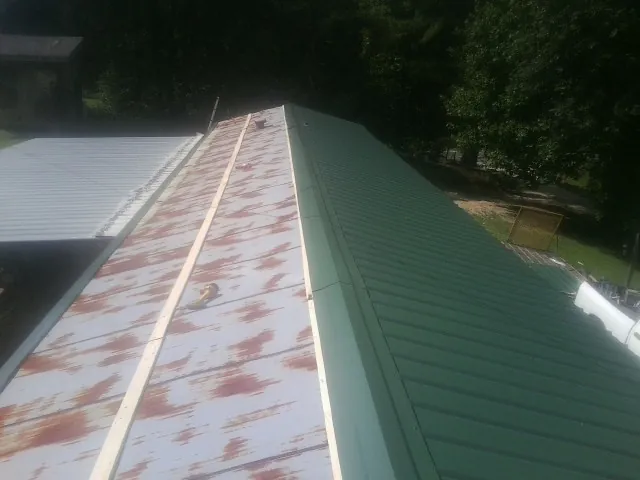 Old rusted panels beside newly installed green metal roofing — Wind Damage Roof Repair by Roofing Brothers in Counce