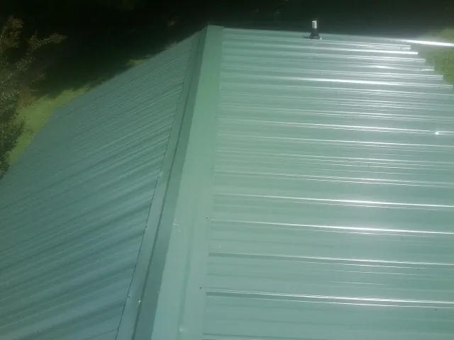 New green metal panels meeting at the ridge of a roof — Flat Roof Repair work by our crew in Counce