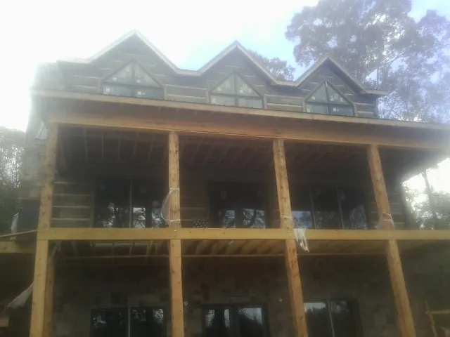 Dormers and porch framing on a large log home under construction — Roof Coating work by our crew in Counce