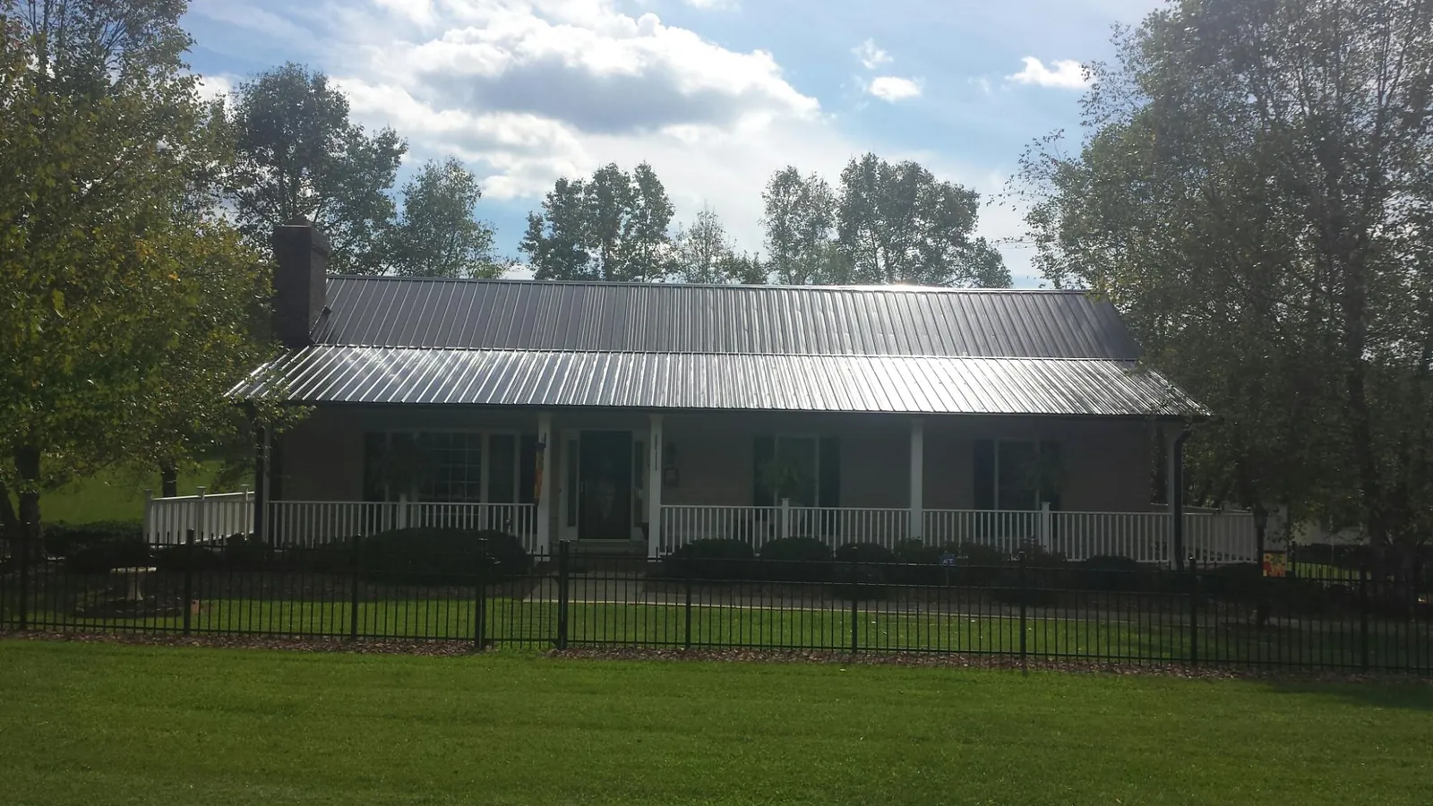 Gray metal roof on a brick ranch with a full width front porch — Gutter Guard Installation work by our crew in Counce
