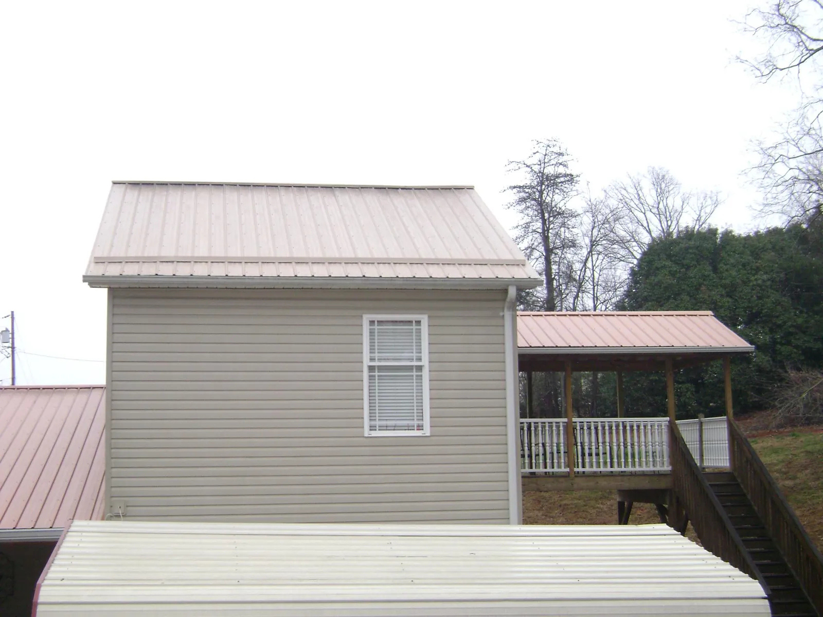 Tan metal roofs on a two story addition and attached porch, from a Roof Replacement job in Counce