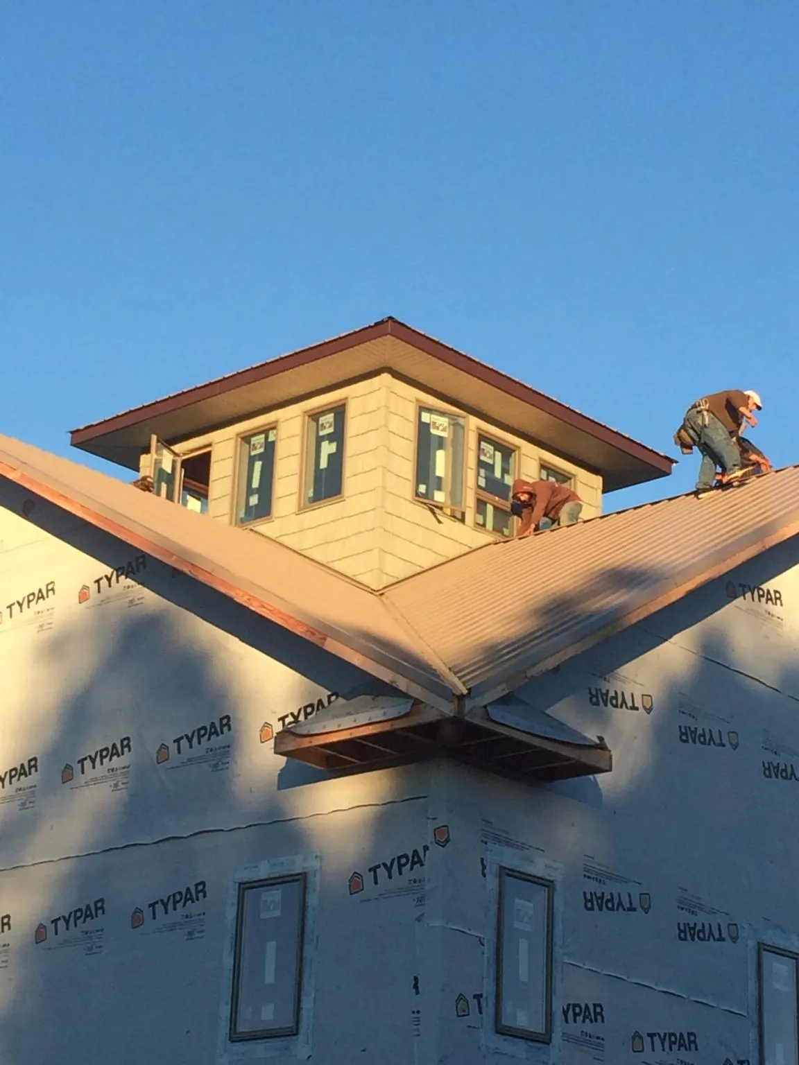 Roofers working around a rooftop cupola on a new metal roof at sunset — Roof Waterproofing in Counce by Roofing Brothers